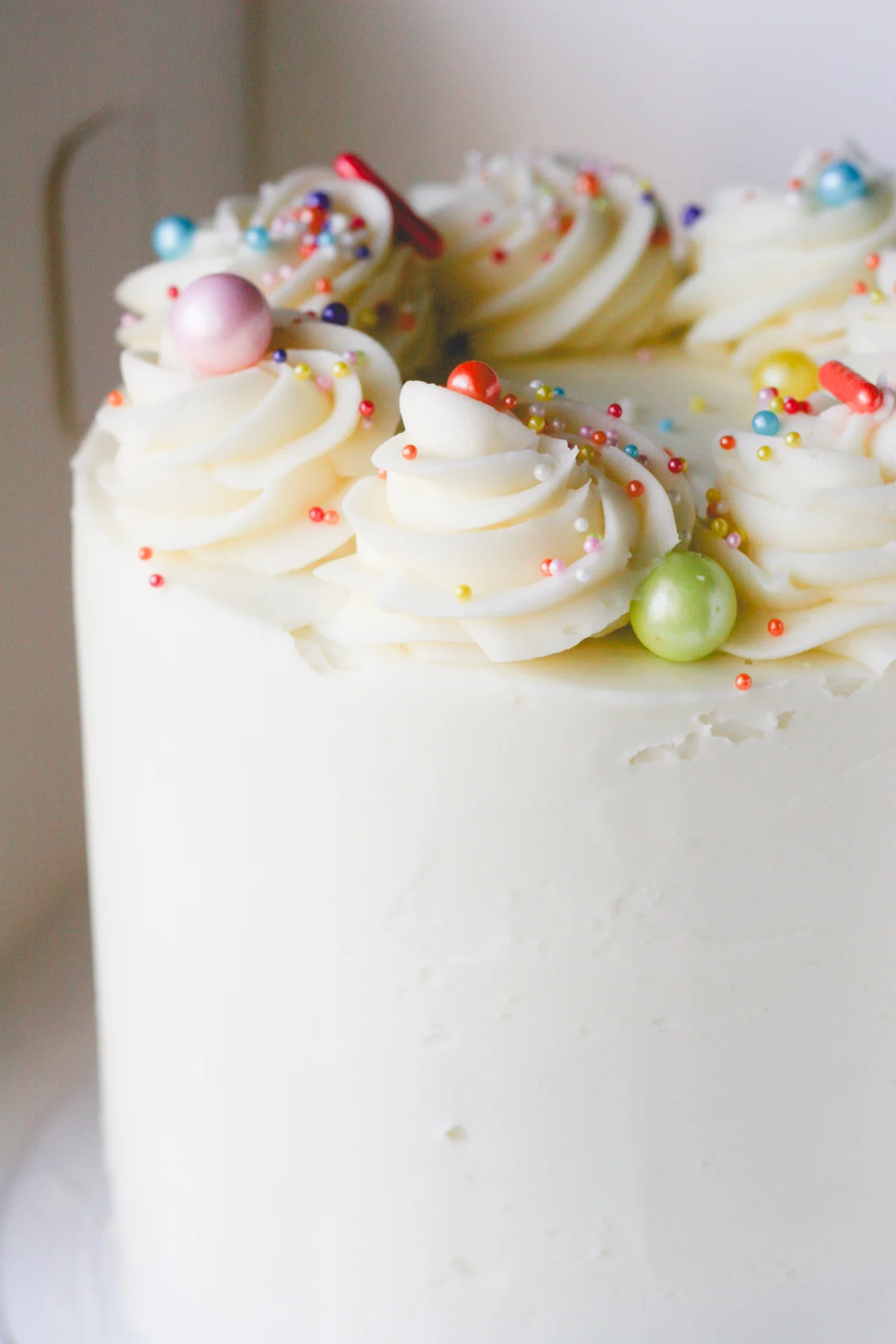 White buttercream cake with piped swirls and colorful sprinkles