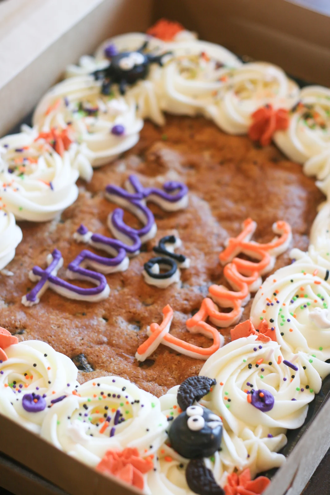 Halloween cookie cake with orange and purple icing and candy spiders