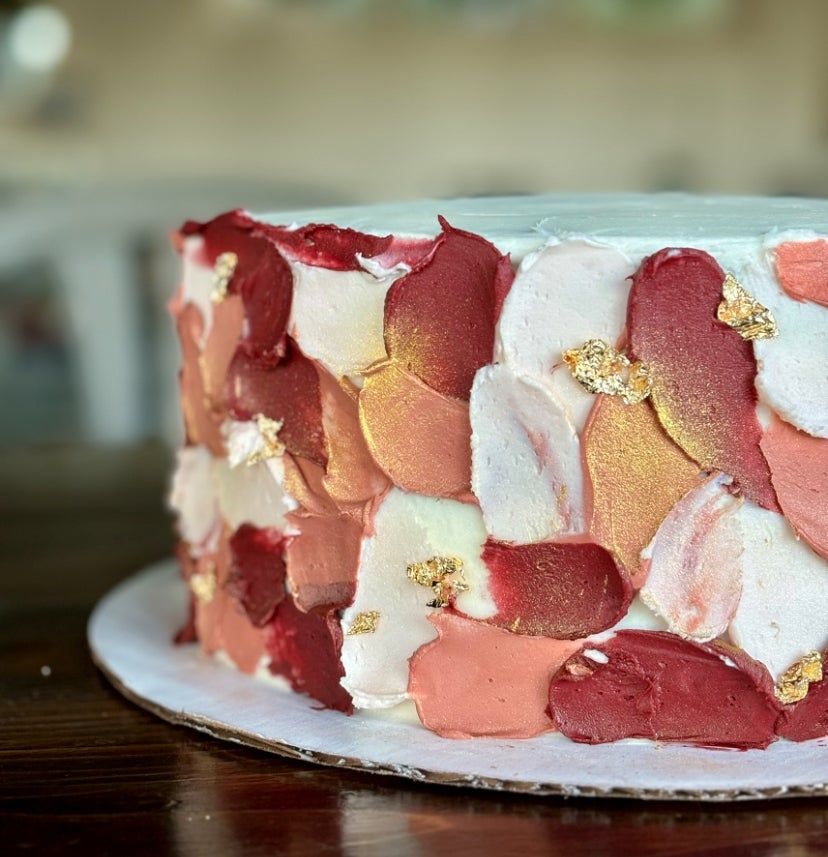 A buttercream cake painted with coral and blush strokes