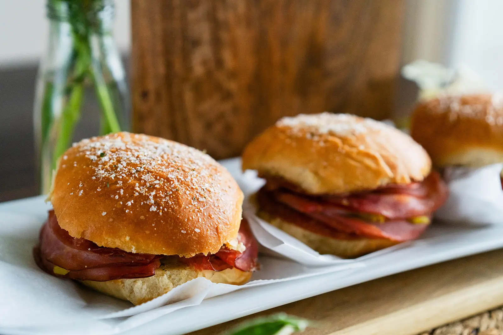 Salt-topped sliders on brioche buns in a white paper tray